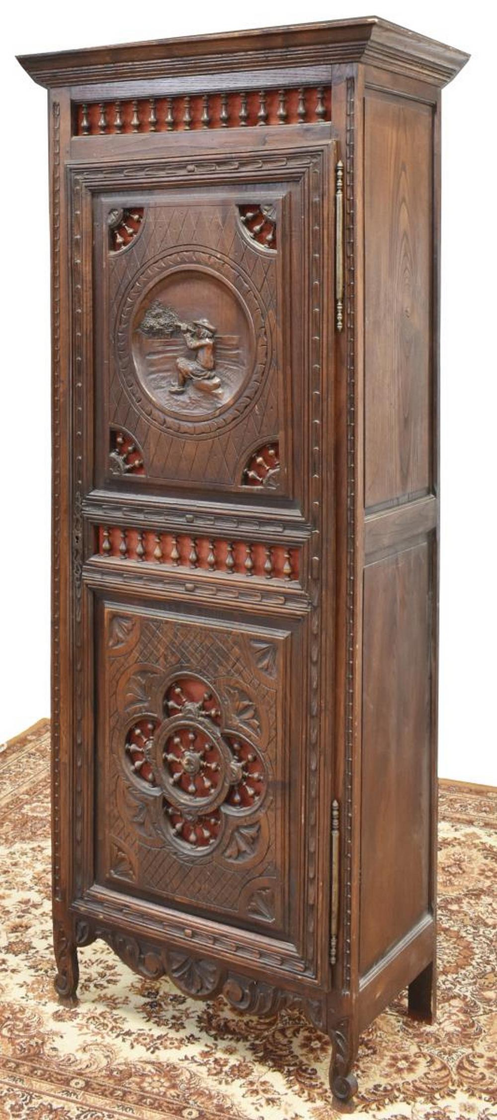 FRENCH BRETON CARVED OAK SINGLE-DOOR ARMOIRE: French Breton oak single-door armoire, 19th c., molded cornice, over open spindle gallery, single door with upper panel depicting seated figure, lower panel with spindle and foliate motifs, opening to