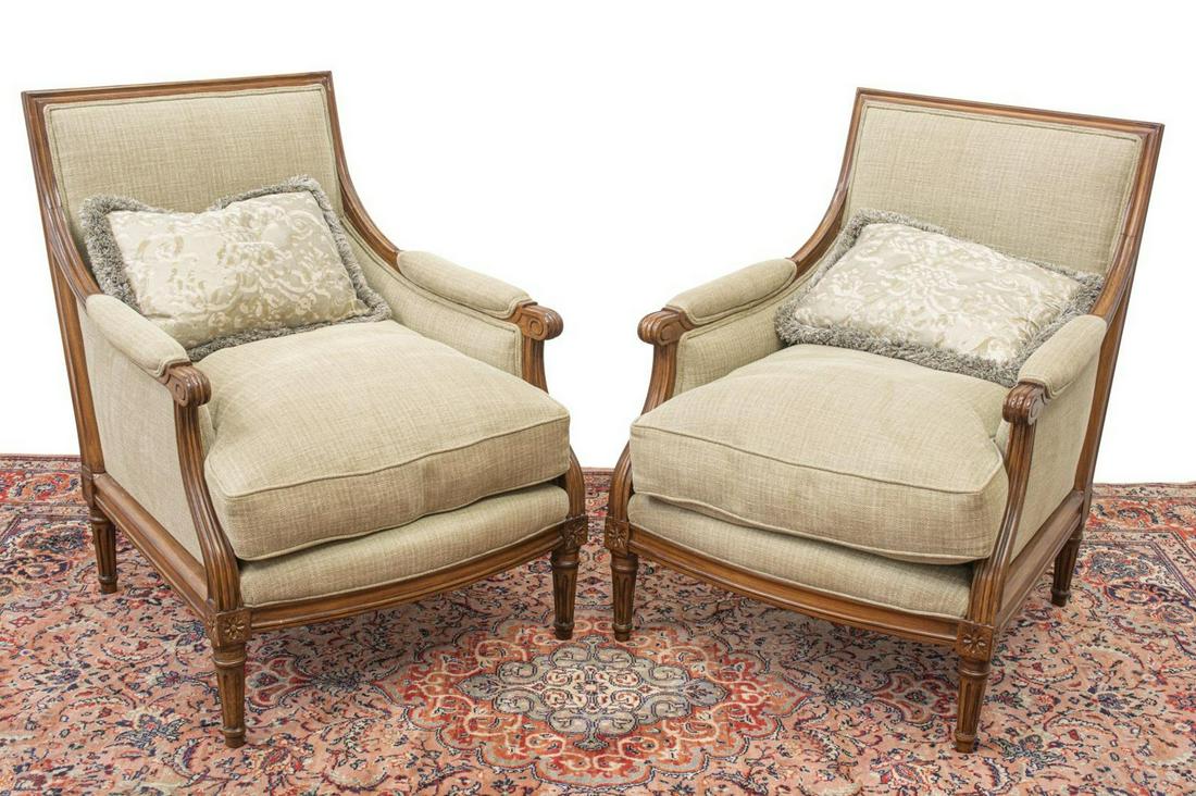 (2) LOUIS XVI STYLE UPHOLSTERED BERGERES: (pair) Louis XVI style armchairs, 20th c., each having fluted walnut frame, tan upholstery to arms, back and removable seat cushion, armrests terminating in scrolled handholds, on fluted tapered legs,