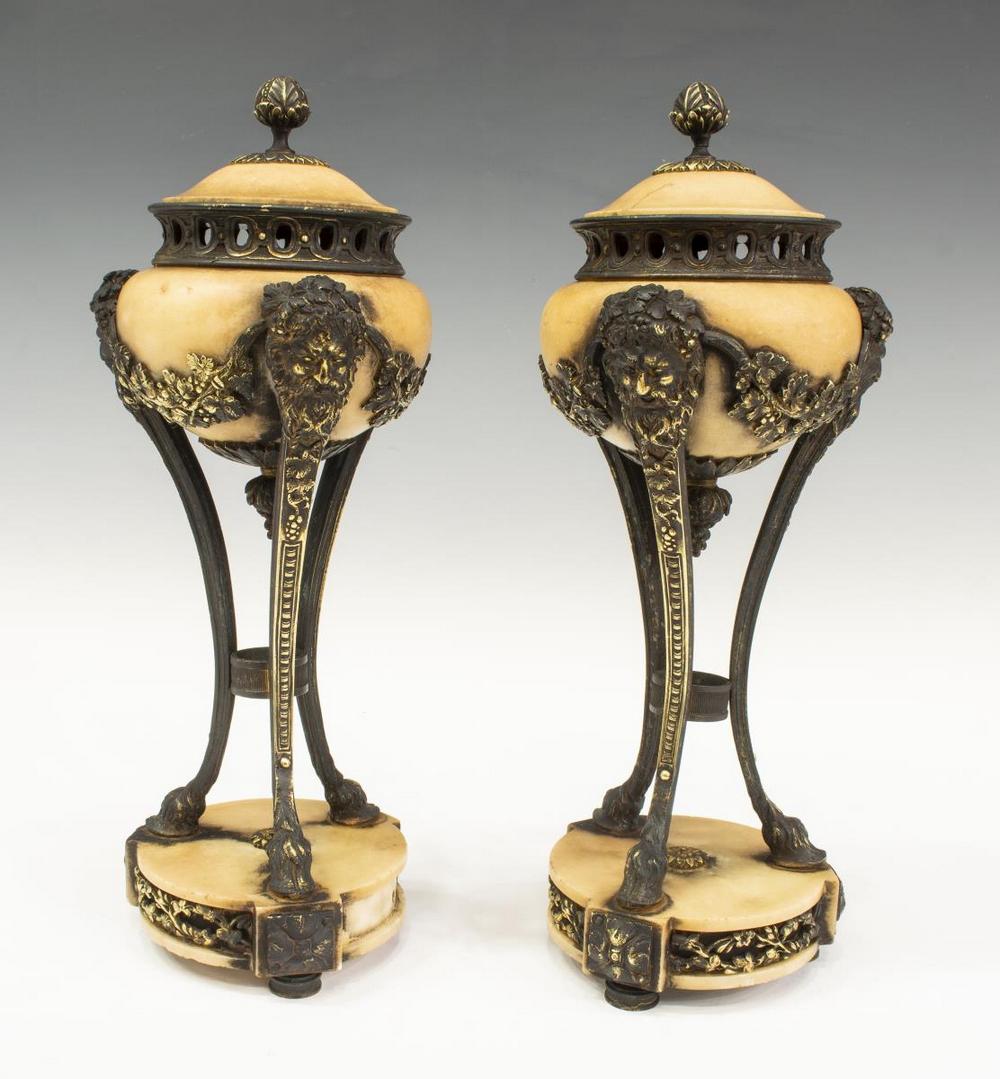 (2) FRENCH LOUIS XVI STYLE URN-FORM CASSOLETTES: (pair) French Louis XVI style stone urn-form garnitures, finial to lid, with bearded figural heads, rising on three narrow parcel-gilt legs terminating in hoof feet, on circular base, one lid intact w