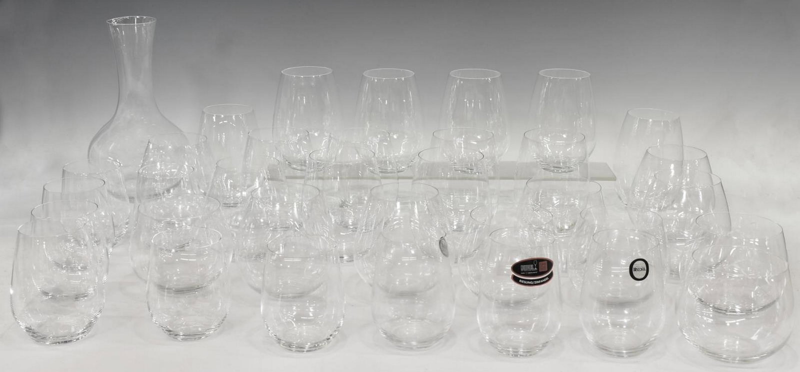 (35) RIEDEL COLORLESS STEMLESS GLASSES & DECANTER: (lot of 35) Riedel colorless stemless wine glasses and decanter, all having acid etched mark underfoot, comprising: (4) Riesling/ Zinfandel glasses, approx 4.25"h, 2.25"diam, (6) Syrah wine glasses, a