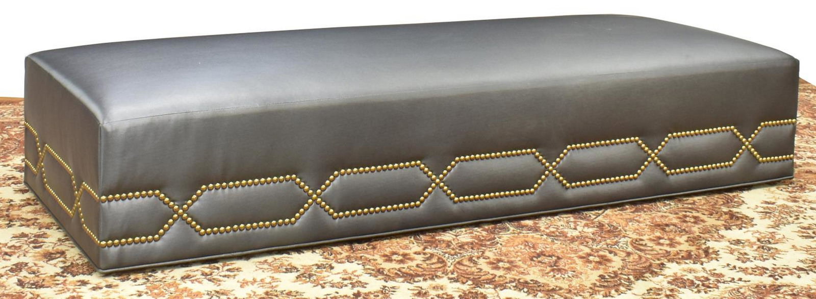 CONTEMPORARY KRAVET FURNTIURE LOW OTTOMAN BENCH: Contemporary low ottoman/ bench, Kravet Furniture, Bethpage, New York, late 20th c., having dark polyester fiber upholstery to padded bench, with brass tacks in a geometric motif, on wheels, retaining