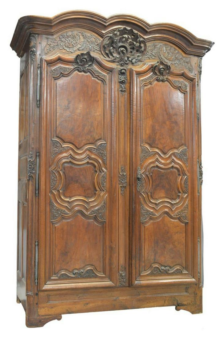 MONUMENTAL FRENCH PROVINCIAL WALNUT ARMOIRE 18TH C: Monumental French Provincial walnut armoire, 18th c., triple arched cornice, expressively carved rocaille crest, paneled double doors with relief carving, on large exterior hinges, iron lock, interior