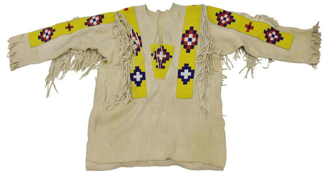 BLACKFOOT BEADED HIDE FRINGE SHIRT, C.1930-1950: Native American beaded hide shirt, Blackfoot, c.1930-1950, fringe, arms: approx 24"l, collar to hem: approx 30"l, 6.25lbs Start Price: $200.00