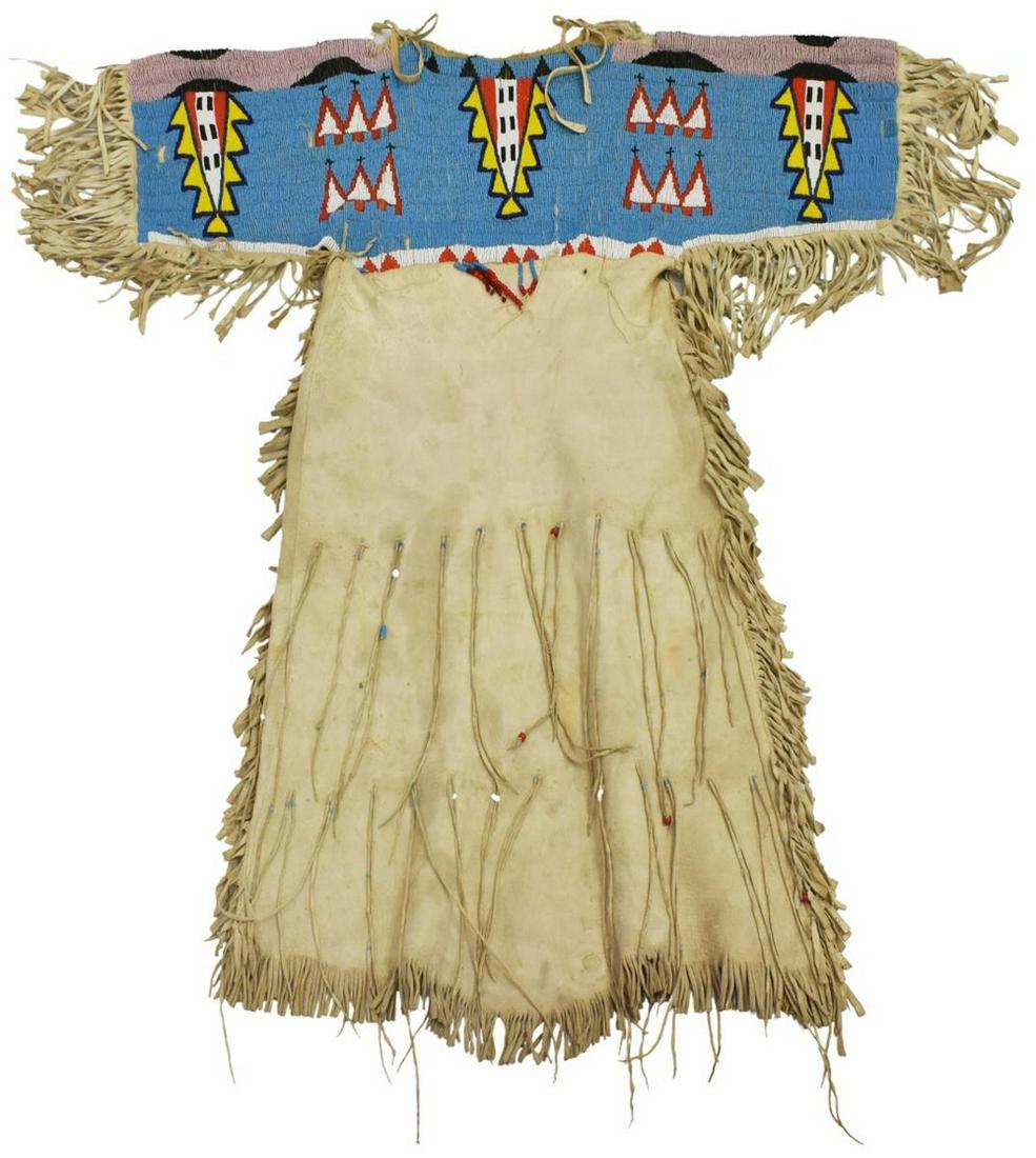SIOUX BEADED HIDE GIRL'S DRESS, C.1910-1925: Native American beaded hide girl's dress, Sioux, c.1910-1925, the upper part fully beaded front and back, sleeves: approx 10"l, collar to fringe hem: approx 43"l, 20"w, 5.25lbs Start Price: $300.00