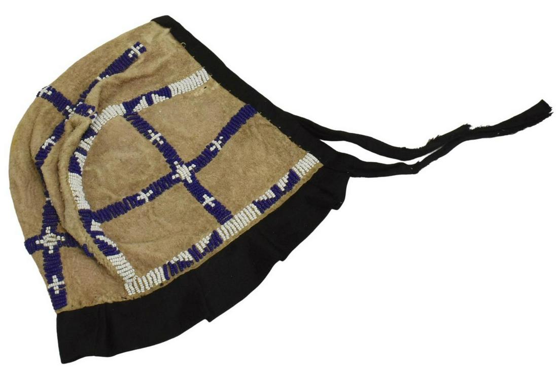 SIOUX BEADED HIDE BABY BONNET, C.1890-1910: Native American beaded hide baby bonnet, Sioux, c.1890-1910, cloth trim, longest measurements: approx 7"h, 8.5"w Start Price: $125.00