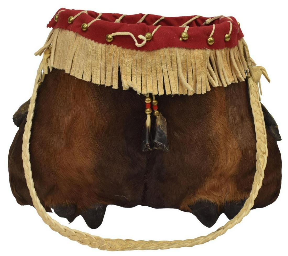 ATHABASCAN MOOSE OR ELK HIDE BAG, C.1950-1980: Athabascan moose or elk hide bag, c.1950-1980, with dew claws on fur, smaller deer dew claws hanging from upper fringe, brass bead decoration, braided hide handle, approx 10.5"h, 13.5"w, 9"d, 2lbs Sta