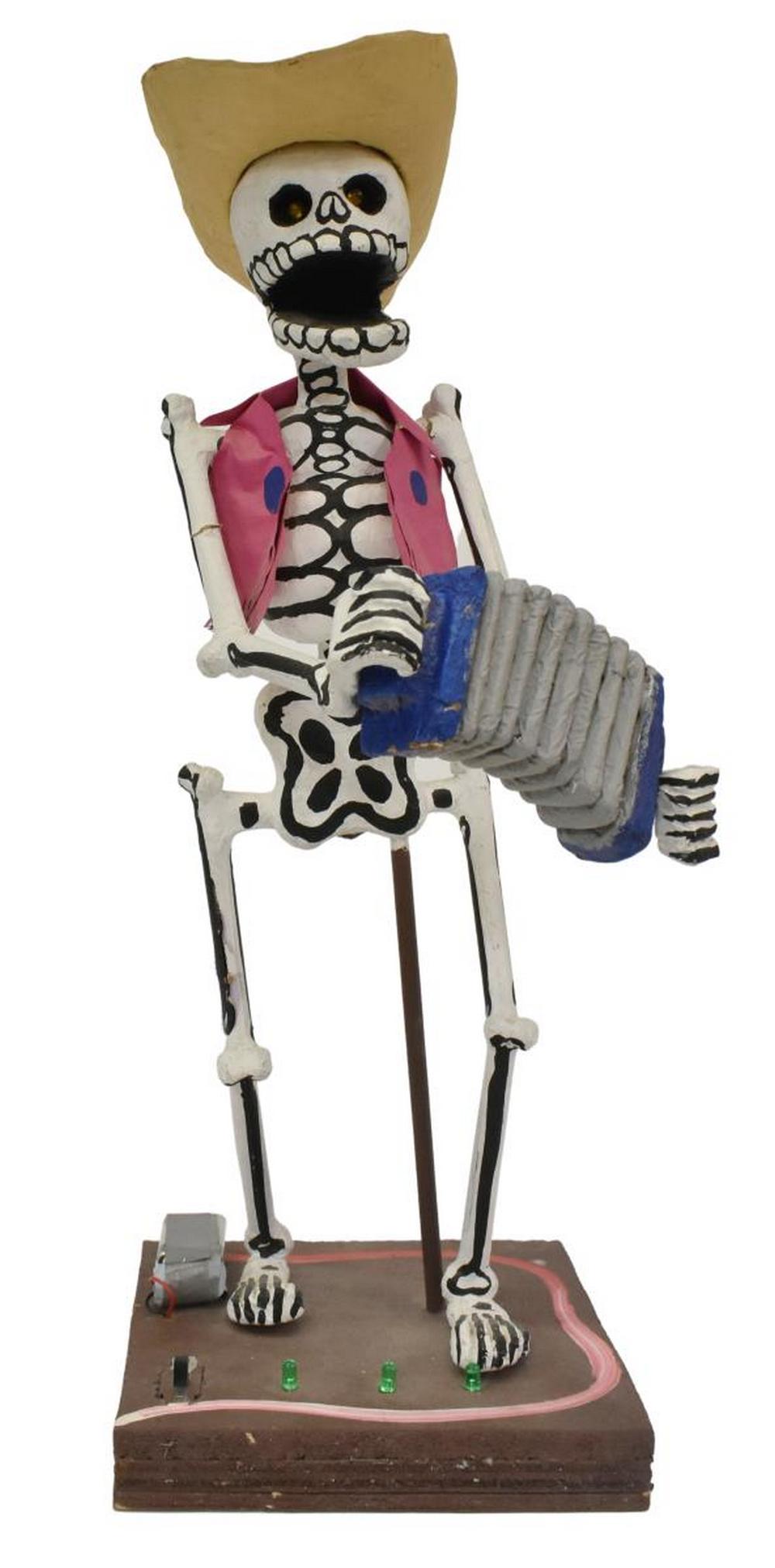 DAY OF THE DEAD PAPIER-MACHE SKELETON W/ ACCORDION: Day of the Dead papier-mache skeleton, Mexico, modeled as cowboy playing an accordion, battery-operated lights in the eyes and on the base, approx 18.5"h, base: approx 6.75"w, 6.75"d, 1.25lbs Start Pr