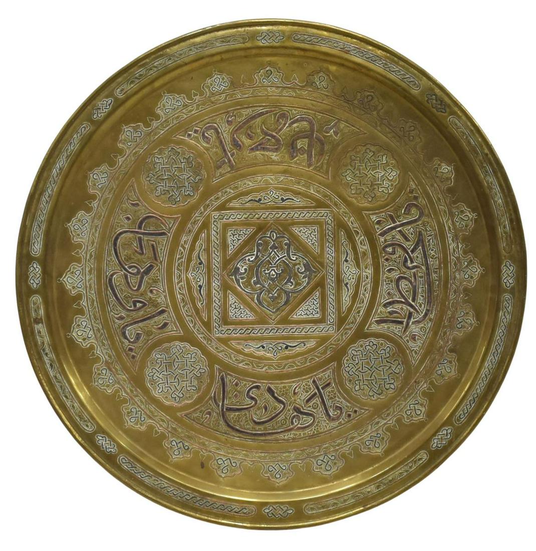 LARGE ISLAMIC MIXED METAL INLAID BRASS CHARGER: Large Islamic brass wall charger, with mixed metal inlays, arabesque and calligraphic motifs, some spotting and patination, approx 26.25"diam, 9.5lbs **Provenance: From the estate of Ali A. Abssi (193