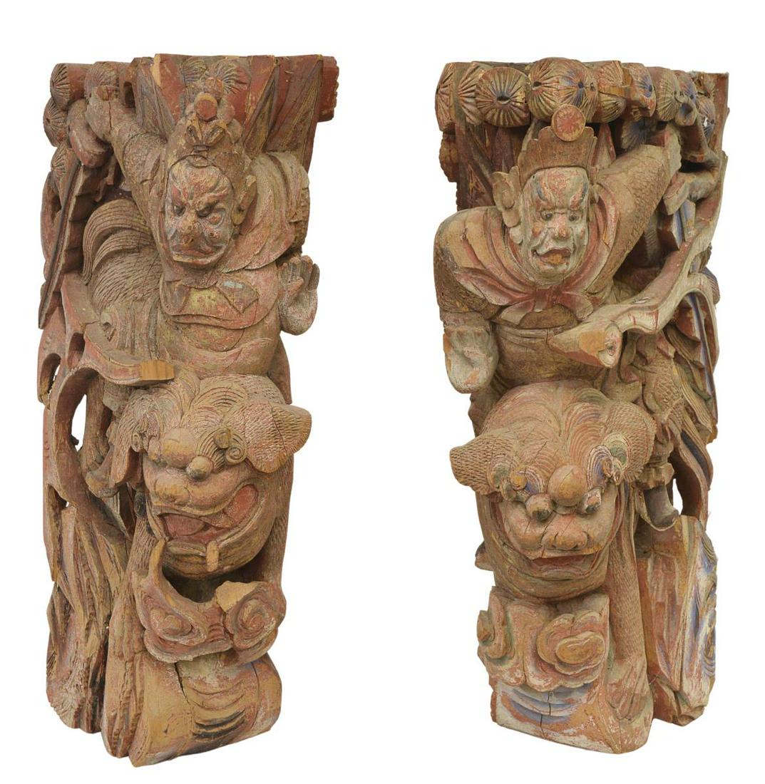 (2) CHINESE CARVED ARCHITECTURAL ELEMENTS CORBELS: (pair) Large Chinese carved wood architectural elements/ corbels, each featuring armed figure with one hand raised, on the back of a foo-lion, remnants of polychrome paint, approx 30.5"h, 8.5"w, 16.5"