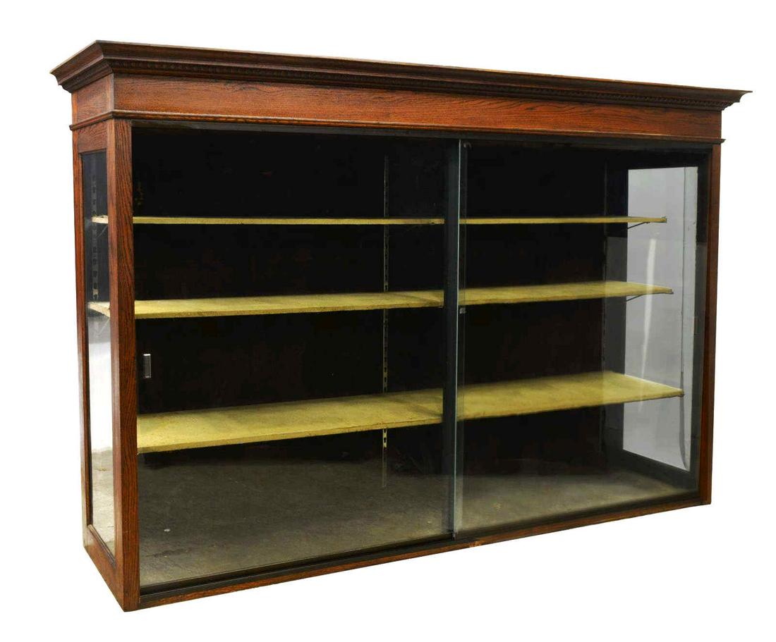 AMERICAN TEXAS OAK & GLASS RETAIL DISPLAY CASE: American oak and glass display case, Southwest Showcase, Dallas, Texas, c.1920s, cornice with egg-and-dart molding, case fitted with two large sliding glass doors, interior fitted with three adjustabl