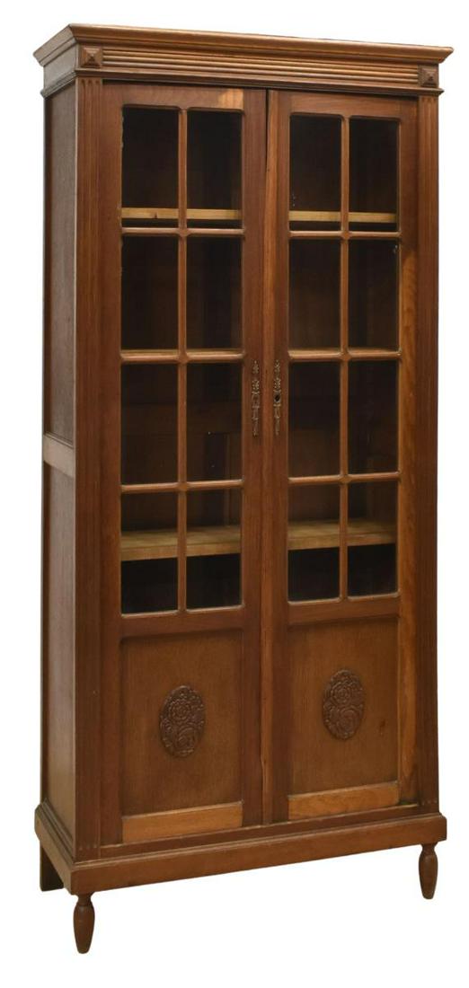FRENCH ART NOUVEAU OAK BOOKCASE/ VITRINE: French Art Nouveau oak bookcase/ vitrine, early 20th c., molded cornice, case fitted glazed double doors, carved with stylized foliate motifs, opening to three adjustable-height shelves, rising on tap
