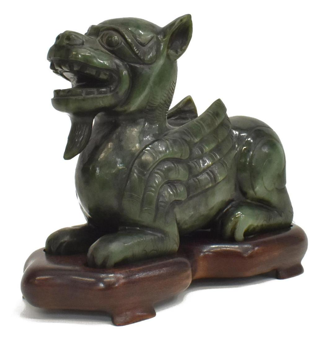 CHINESE CARVED SPINACH GREEN HARDSTONE CHILONG: Chinese carved spinach green hardstone dragon/ chilong, on hardwood stand, approx 5 5/8"h, 7.5"l, 2.5"w (measurements not including stand), 5lbs **Provenance: From the estate of Ali A. Abssi (1934-202