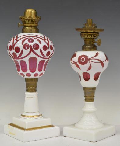 (2) WHITE CUT TO CRANBERRY CASED GLASS OIL LAMPS: (lot of 2) Victorian white cut to cranberry cased glass oil lamps, 19th c., (one) with Holmes, Booth and Haydens burner, (one) with EM & Co. "Boudoir" burner, largest: approx 13.5"h, 4.5"w, 4.5"w; 5.5