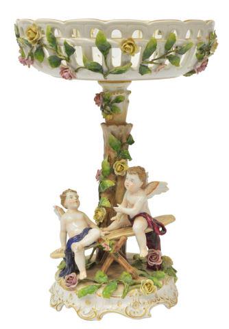 GERMAN SCHIERHOLZ PORCELAIN CENTER BOWL COMPOTE: German porcelain compote, Schierholz, parcel gilt reticulated bowl, applied vining flowers continuing to central standard, rocaille base with seated winged putti, typical small flakes to applied eleme
