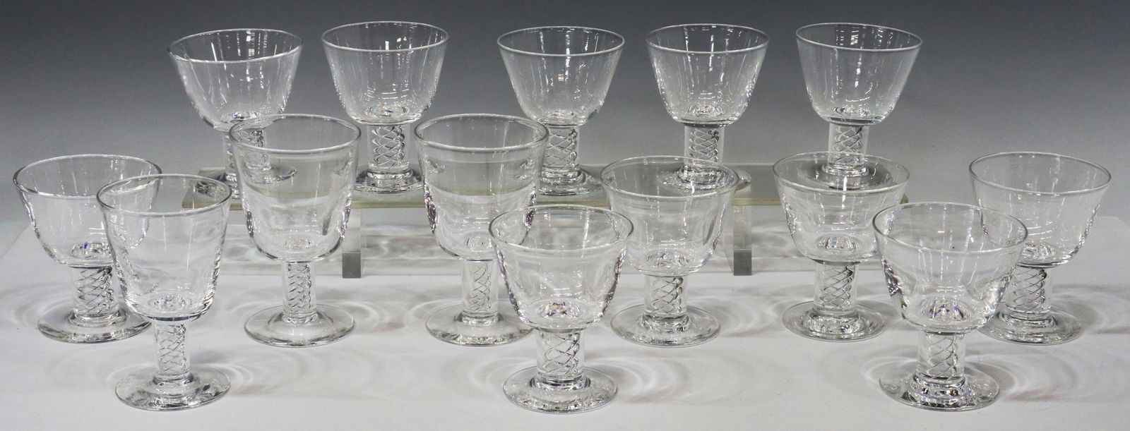 (14) STEUBEN AIR TWIST STEM GLASS STEMWARE: (lot of 14) Steuben colorless leaded art glass stemware, designed by George L. Thompson (American, 1913-1981), second half 20th c., with air twist stem, engraved signature underfoot, including: (11) a
