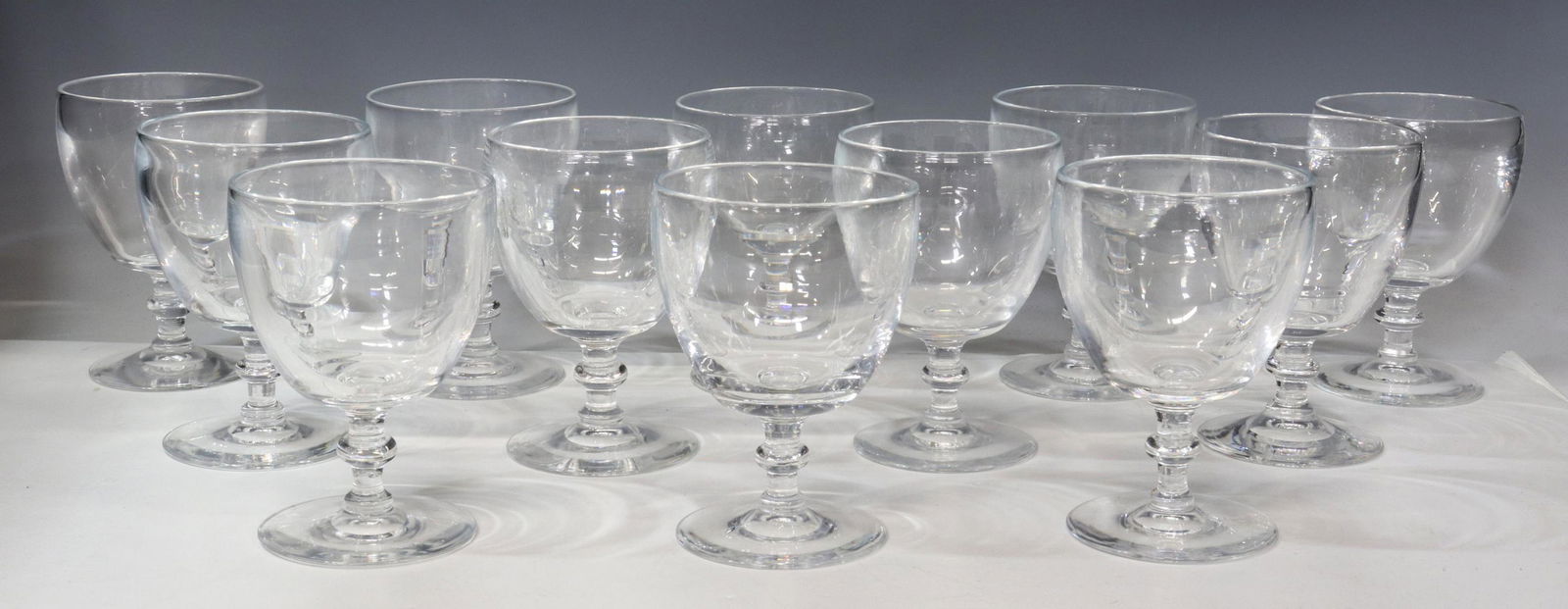 (12) STEUBEN ART GLASS 6268 WATER GOBLETS: (lot of 12) Steuben colorless leaded art glass water goblets, designed by Frederick Carder (1863-1963), pattern number 6268, tapered bowl, wafer stem, on a circular foot, (nine) with engraved signatur