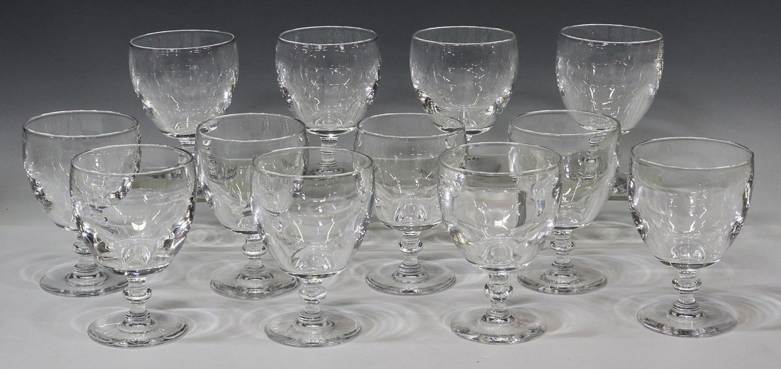 (12) STEUBEN ART GLASS 6268 WATER GOBLETS: (lot of 12) Steuben colorless leaded art glass water goblets, designed by Frederick Carder (1863-1963), pattern number 6268, tapered bowl, wafer stem, on a circular foot, engraved signature underfoot,