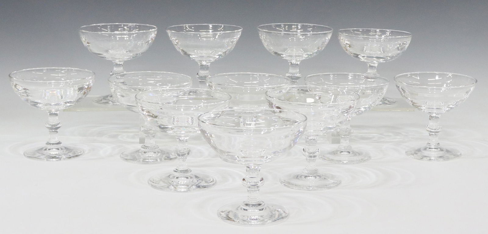 (12) STEUBEN ART GLASS 6268 CHAMPAGNE COUPES: (lot of 12) Steuben colorless leaded art glass champagne coups/ tall sherbets, designed by Frederick Carder (1863-1963), pattern number 6268, shallow bowl, wafer stem, on a circular foot, engraved sig