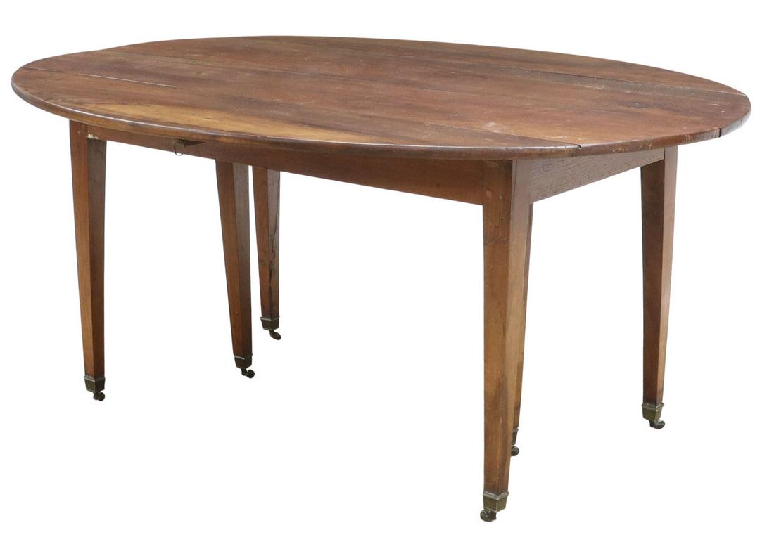 FRENCH WALNUT DROP-LEAF TABLE: French walnut drop-leaf table, late 19th c., having oval top, rising on tapered legs, ending in metal-capped feet, on casters, approx 27"h, 59"w, 24"d, with leaves: 47"d Start Price: $250.00
