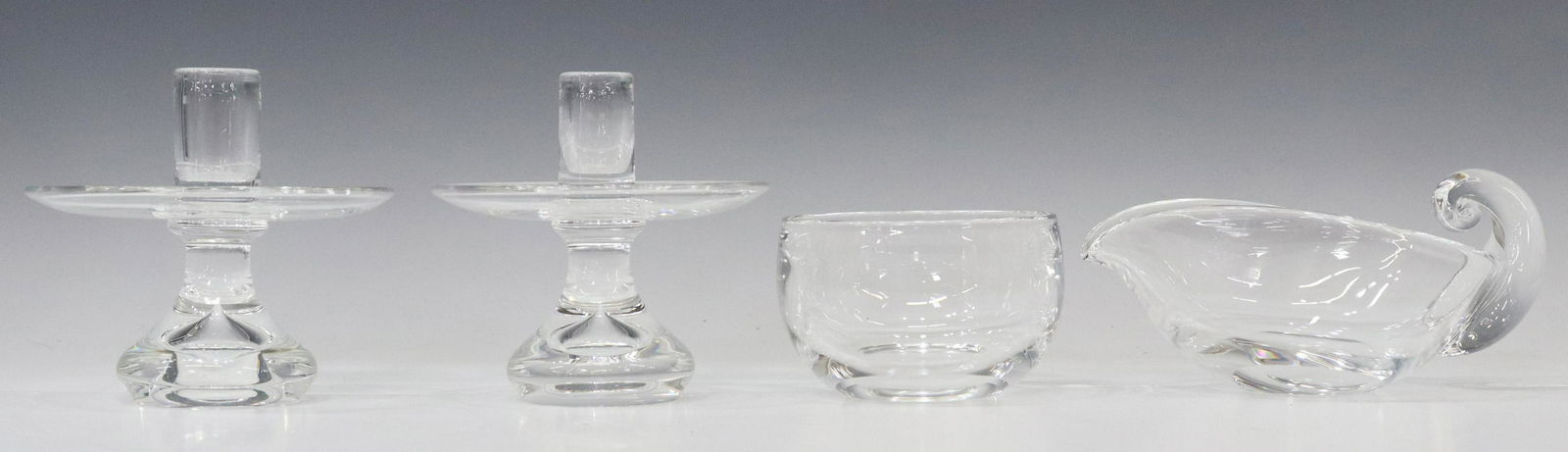 (4) STEUBEN GLASS SAUCE BOAT, BOWL, CANDLESTICKS: (lot of 4) Steuben colorless leaded art glass tableware, mid 20th c., including: (1) pear-shaped gravy/ sauce boat, designed by Lloyd Atkins (American, b.1922), with snail scroll handle, approx 3.5"h,