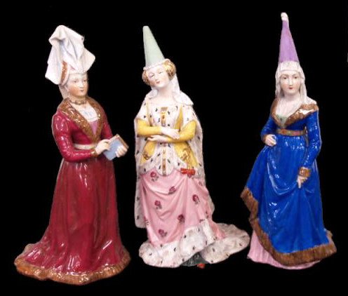 FINE ANTIQUE SEVRES-STYLE PORCELAIN QUEEN FIGURES: (Lot of 3) A collection of Sevres-style porcelain figures formed as medieval queens: one dressed in a red, fur-trimmed gown with a towering headdress, holding a book with gilt detailing on book and ne