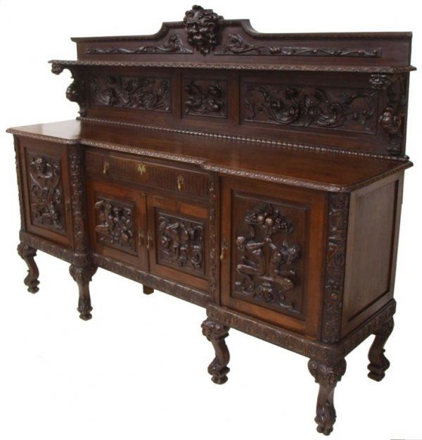 ANTIQUE SPAIN RELIEF CARVED FIGURAL SIDEBOARD: Sizeable Spanish walnut sideboard, 19th c., relief carving throughout depicting mythical figures, winged angel masks, grotesques and griffins, a two-tier backsplash surmounting the case housing a sing