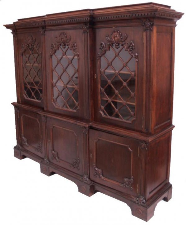 ANTIQUE SPANISH TRIPLE DOOR WALNUT BOOKCASE & SAFE: Spanish triple door walnut bookcase in two-parts, c., 1920, the upper case set with a row of glazed doors enhanced with lattice work, three cabinet doors below conceal storage, one set with an "Ariso,