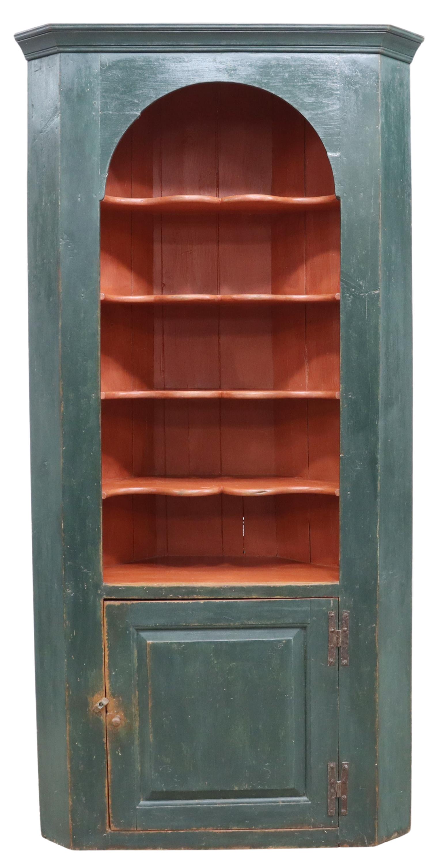 CONNECTICUT PAINTED PINE CORNER CUPBOARD, 18TH C.: American painted corner cupboard, Connecticut, 18th c., triangular pine case having molded cornice over arched front enclosing four bow shaped open shelves, single cabinet door fitted with iron h-hing