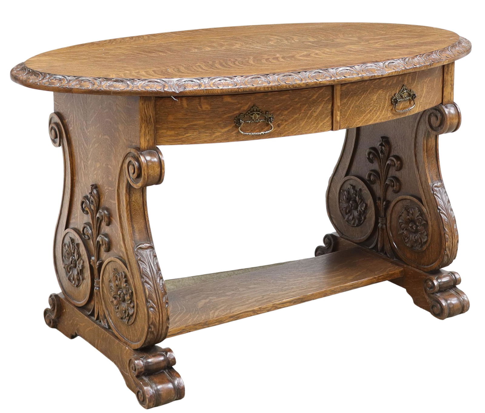 ORNATE AMERICAN OAK OVAL TWO-DRAWER LIBRARY TABLE: American quarter sawn oak library table, c.1900, oval top with carved shell border, over two curved drawers, rising on lyre-form trestle base, decorated with floral and foliated spiral motif, approx 3
