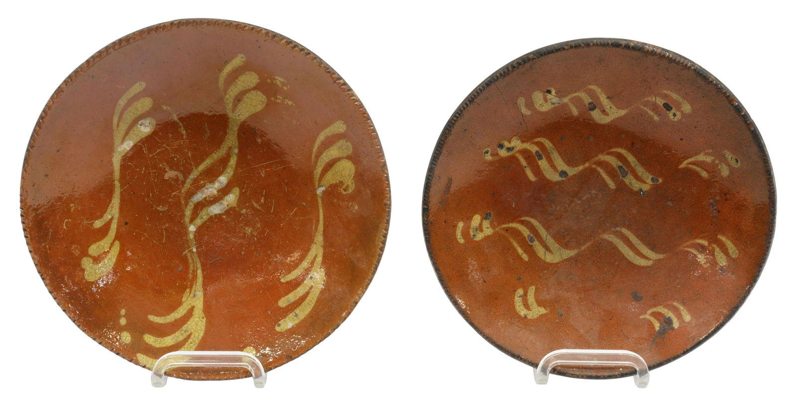 (2) AMERICAN SLIP-DECORATED REDWARE POTTERY PLATES: (lot of 2) American slip-decorated redware pottery plates, New England, 19th c., having a coggled rim, encircling linear yellow slip cup designs, unglazed bottom, expected rim and glaze chips, crazing