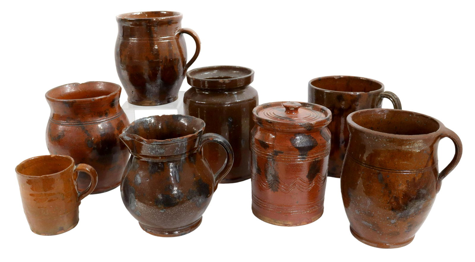 (8) AMERICAN REDWARE POTTERY: MUGS, TANKARDS, ETC.: (lot of 8) American redware pottery, 19th c., including: (1) mug, New England, approx 5.5"h, (1) cup with strap handle, New Hampshire, approx 3.5"h, (1) incised jar with manganese decoration, New Engl