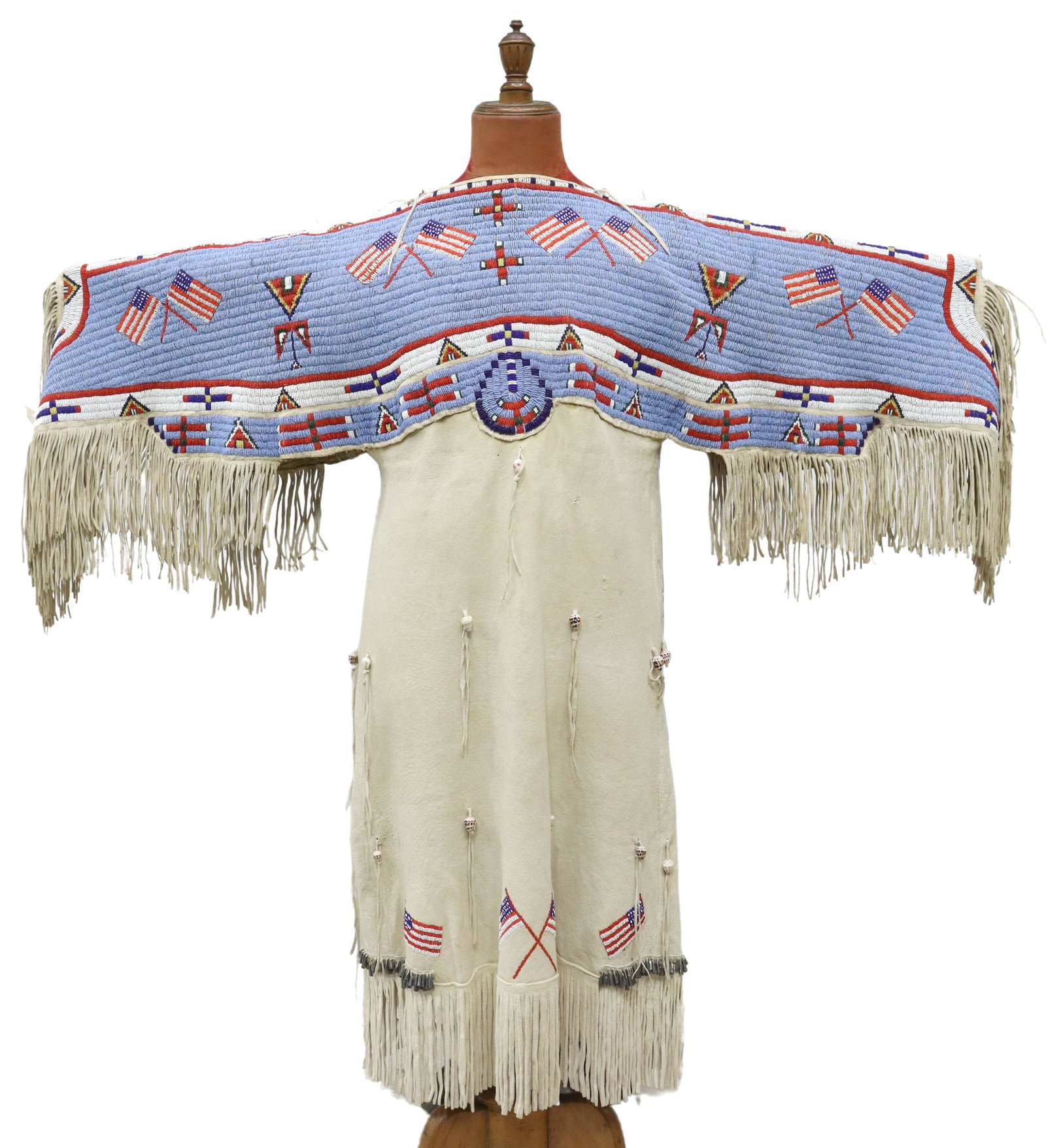 NATIVE AMERICAN SIOUX BEADED PICTORIAL DRESS: Sioux beaded deer hide fringed pictorial dress, c.1920-1940, displaying numerous American flags and symbols, the lower part with fringe and jingle cones, approx. 47"l, 58.5"w *Provenance: New Mexico e