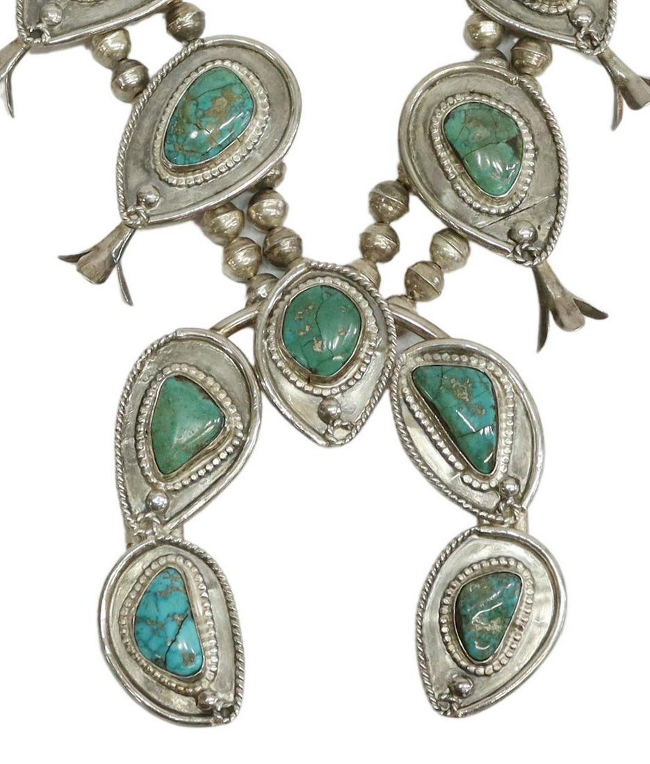 NATIVE AMERICAN TURQUOISE SQUASH BLOSSOM NECKLACE: Native American silver (content unknown) and turquoise squash blossom necklace, featuring eight turquoise-set blossoms and central naja with five varied stones, framed by beaded and twisted wire motif