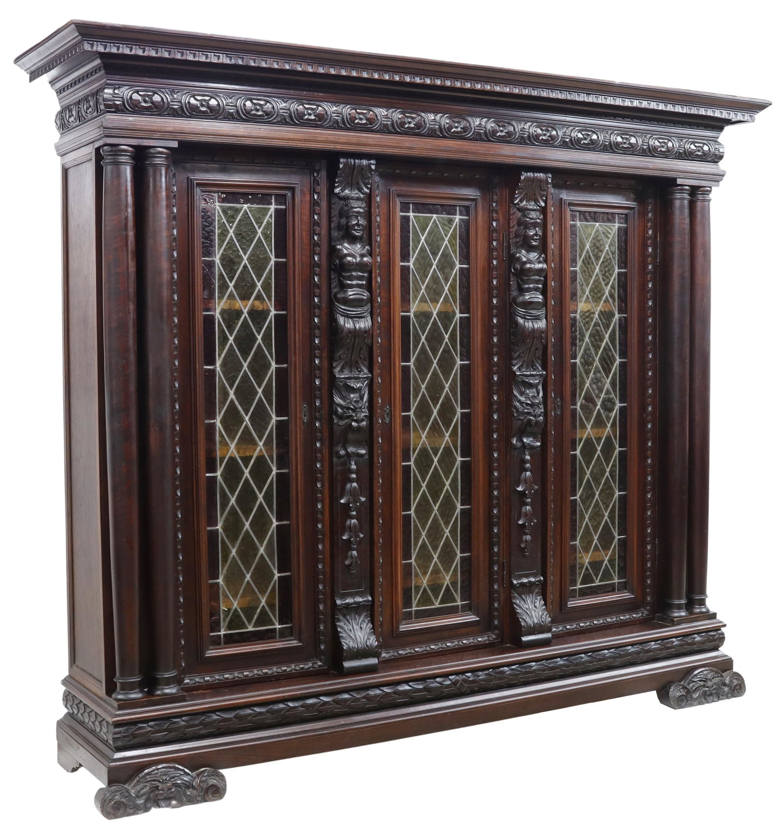 ITALIAN RENAISSANCE REVIVAL STAINED GLASS BOOKCASE: Italian Renaissance Revival bookcase, early 20th c., molded cornice and frieze, carved figural pilasters, turned column supports, three cabinet doors with stained and leaded glass panels, interior she
