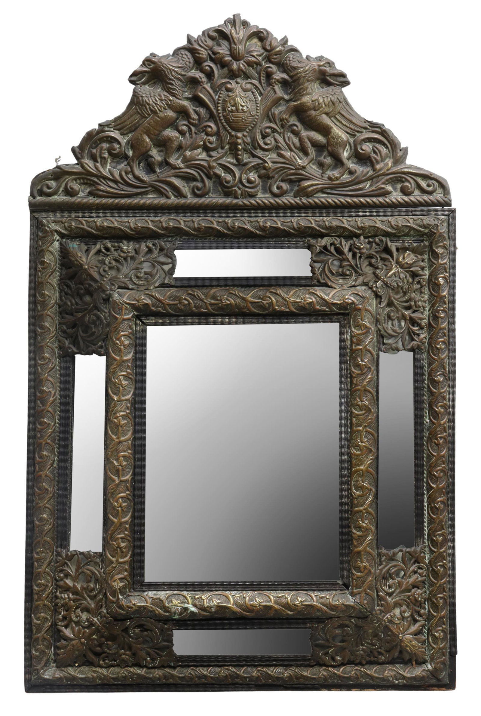 DUTCH BAROQUE STYLE REPOUSSE CUSHION MIRROR: Dutch Baroque style repousse cushion mirror, 19th c., crest with opposing winged griffins centering bellflower cartouche, cushion-form surround with scrolling foliate overlay, segmented mirror plates 