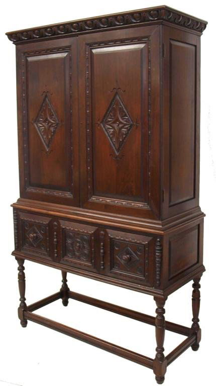 FINE KITTINGER CARVED WALNUT BLIND CHINA CABINET: American Kittinger Furniture Co. carved walnut blind china cabinet, early 20th c., carved ornamentation decorating double doors and deep single drawer, rising on turned supports joined by a box stretc
