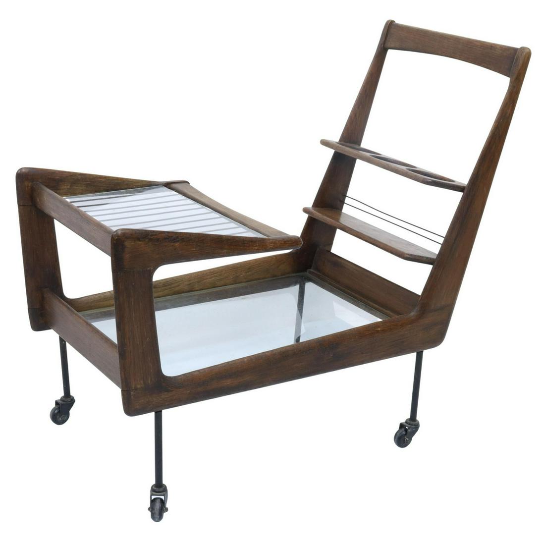 ITALIAN MID-CENTURY MODERN SERVICE/ BAR CART: Italian mid-century modern service/ bar cart, c.1950s, having two glass tiers, rack that accommodates three wine bottles, metal legs, rising on casters, approx 30.75"h, 33"w, 17"d Start Price: $150.00