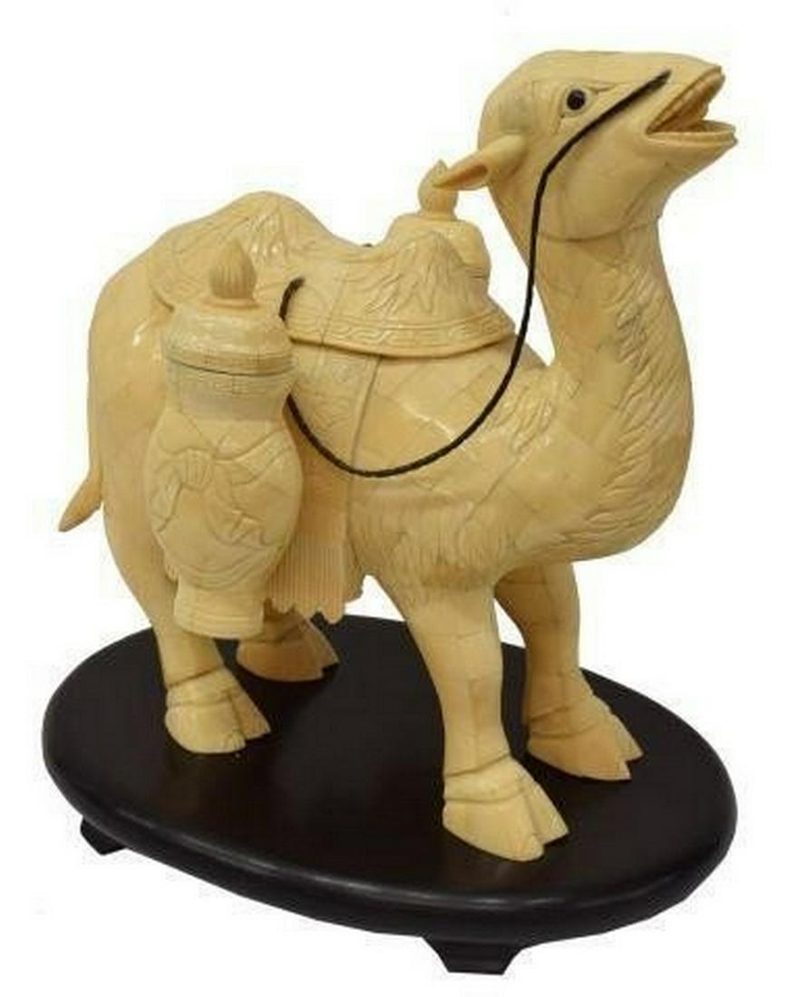 CHINESE TILED BONE STANDING CAMEL FIGURE ON STAND: Chinese tiled bone camel figure, with saddle, reins, and lidded jars to either side, accompanied by wood stand, figure: approx 13.75"h, 13.5"w, 9"d; on stand: approx 15.75"h, 14.25"w, 10.25"d; 10.75lb