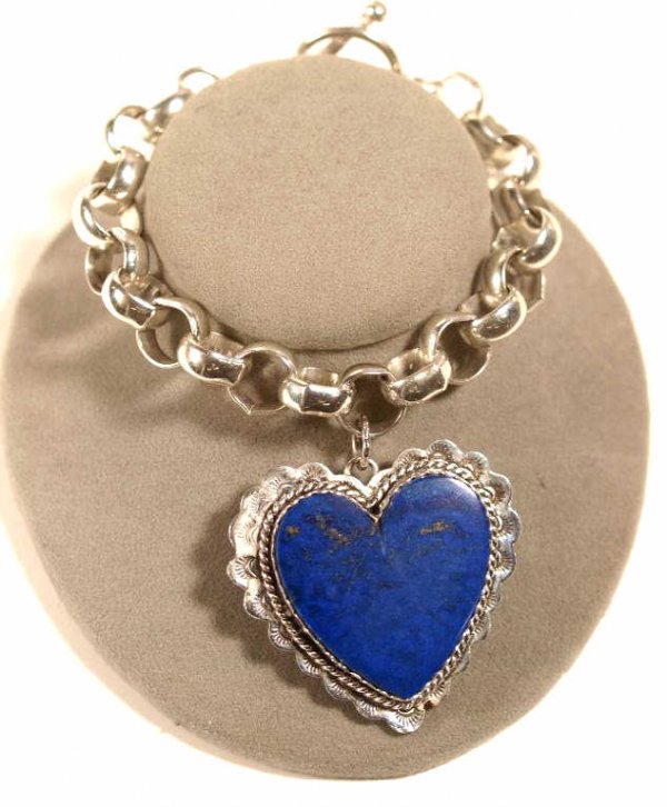 JOAN SLIFKA JEWELRY STERLING, LAPIS HEART BRACELET: Joan Slifka Designs sterling silver bracelet, circular links hold a large dangling heart set with blue lapis on one side, the reverse in relief with two winged cupids poised to shoot a heart, unsigned