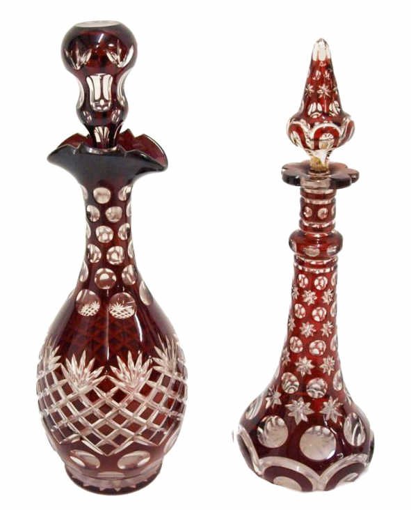 (2) ANTIQUE BOHEMIAN RUBY CUT TO CLEAR DECANTERS: (lot of 2) Fine ruby cut to clear Bohemian glass decanters, late 19th c., (1) cut with geometric star and circle ornaments, loss and restoration to stopper, 11.75"h, 4"d; (1) with cross hatched/diamon