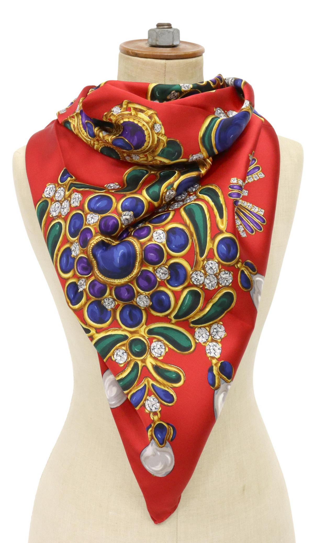 CHANEL RED JEWELS SILK SCARF: Chanel silk scarf, red ground with pattern of emerald, sapphire, diamond, pearl, and amethyst jewels, hand-rolled edges, marked Chanel in gold, retaining original care tag, scarf: approx 35"l, 35"w, 0