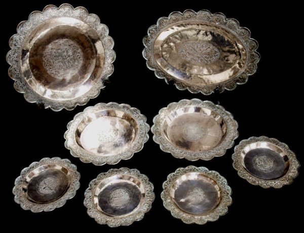 SOUTHEAST ASIAN SILVER TRAYS, KRIS DAGGER MOTIF: (lot of 8) Southeast Asian silver tray group, varied sizes with matched designs, each having a scalloped border with fan and foliate decoration, central reserve featuring a keris and sheath amongst vi