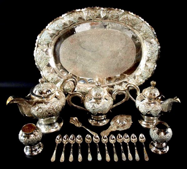 SOUTHEAST ASIAN SILVER PLATE TEA & COFFEE SERVICE: (19 piece set)Southeast Asian silver plate tea and coffee service ornately embossed with blossoms and tendrils, comprising: tray with hammered center, coffee pot and tea pot with bird form spout, hand