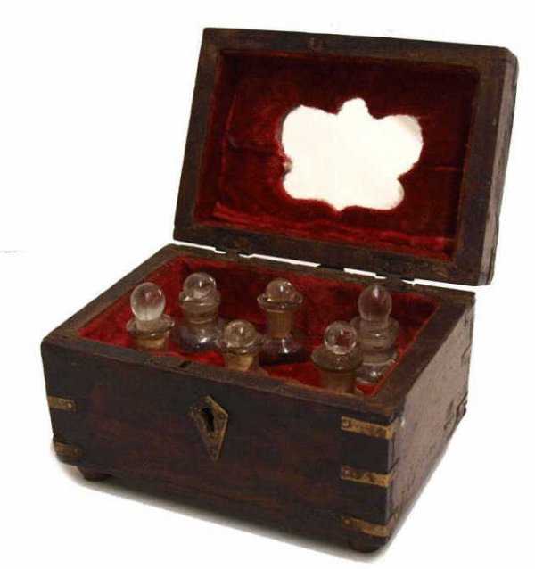 BRITISH COLONIAL BRASS BOUND ROSEWOOD PERFUME BOX: British Colonial brassbound rosewood perfume box, late 19th c., the locking box inlayed with brass and holding (6) enameled, parcel gilt scent bottles of varied form, supported by four wood feet, incl