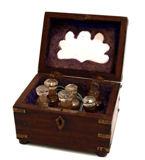 BRITISH COLONIAL BRASS BOUND ROSEWOOD PERFUME BOX: British Colonial brassbound rosewood perfumery box, late 19th c., the diminutive locking box having decorative brass and copper inlays, mirrored and lined interior holding (6) scent bottles of varied 