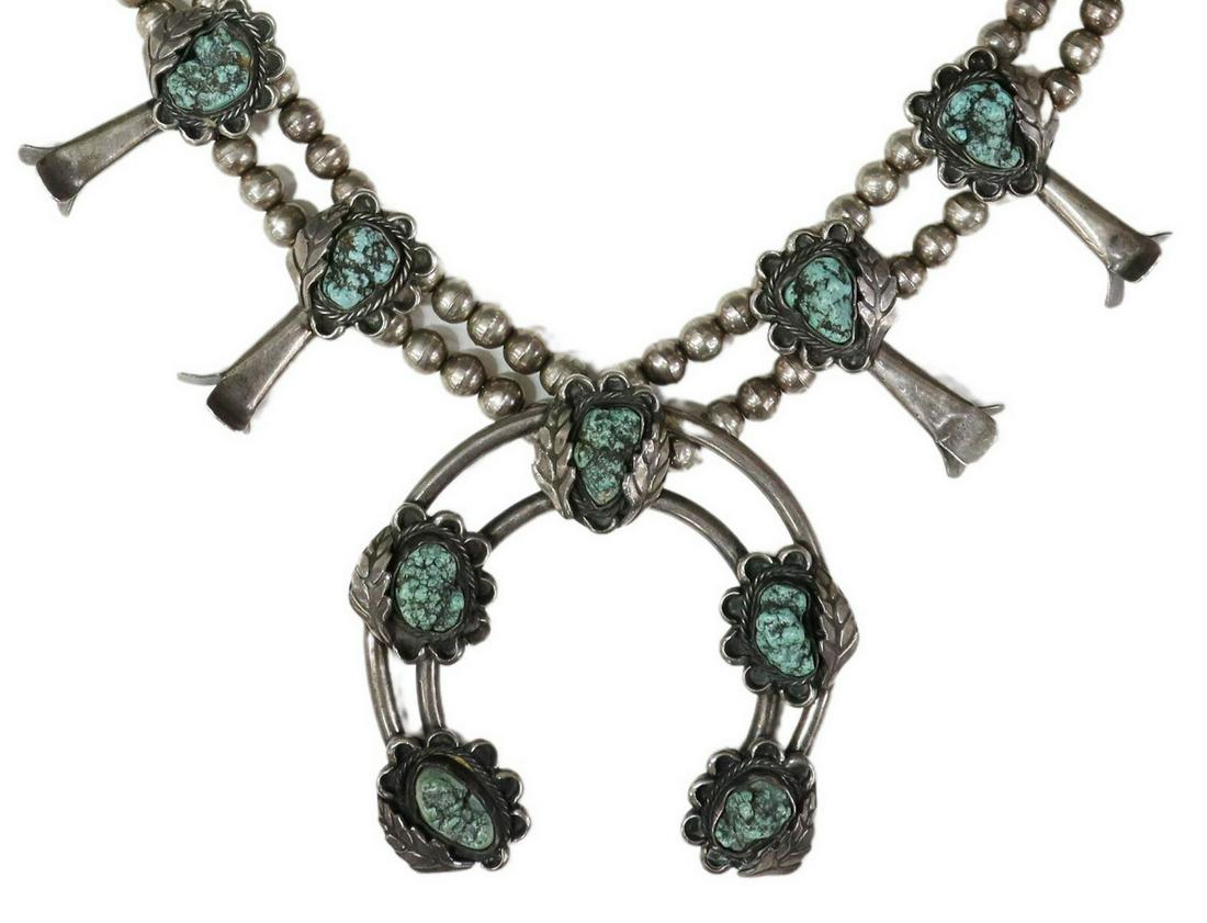 NATIVE AMERICAN TURQUOISE SQUASH BLOSSOM NECKLACE: Native American silver (content unknown) squash blossom necklace, likely Navajo, bench bead strand, ten blossoms, each set with a turquoise nugget, central naja pendant with five turquoise nuggets, ap