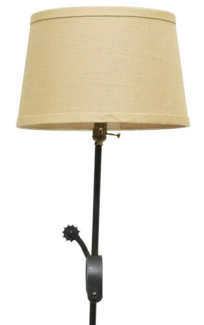WESTERN STYLE WROUGHT IRON & SPUR FLOOR LAMP: Western style wrought iron floor lamp, 20th c., having burlap shade concealing single light, simple standard accented with spur, rising on ring base, approx 64"h, 16"diam Start Price: $80.00