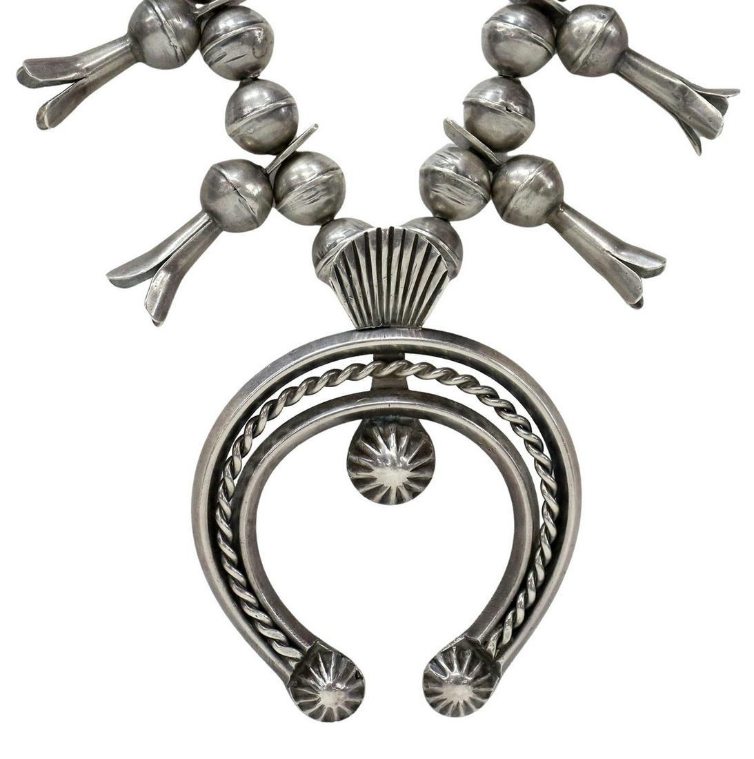 NATIVE AMERICAN SILVER SQUASH BLOSSOM NECKLACE: Native American silver (content unknown) squash blossom necklace, likely Navajo/ Dine, bench bead strand, fourteen blossoms, central naja pendant with twisted wirework, approx 27"l, naja: approx 3.5"h