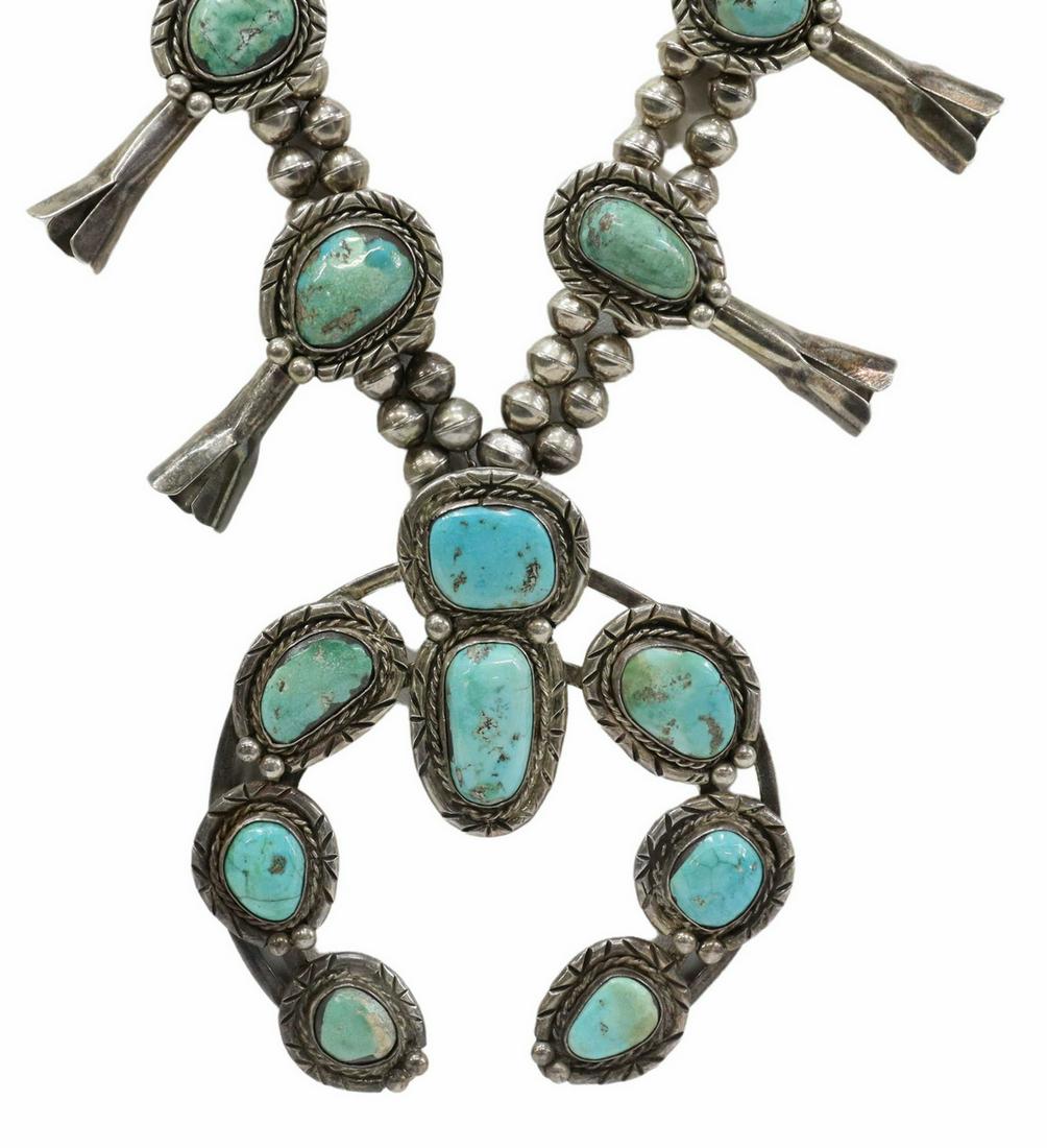 NATIVE AMERICAN TURQUOISE SQUASH BLOSSOM NECKLACE: Native American silver (content unknown) squash blossom necklace, likely Navajo, double bench bead strand ending in a single strand, ten blossoms each set with a turquoise cabochon, central naja penda