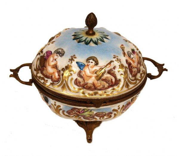 ANTIQUE FRENCH PORCELAIN & GILT METAL DRESSER BOX: Antique French porcelain dresser box with gilt metal mountings, in the Capodimonte style, the whole with scenes of parcel gilt winged cherubs, raised on four gilt metal feel, marked underfoot with N u